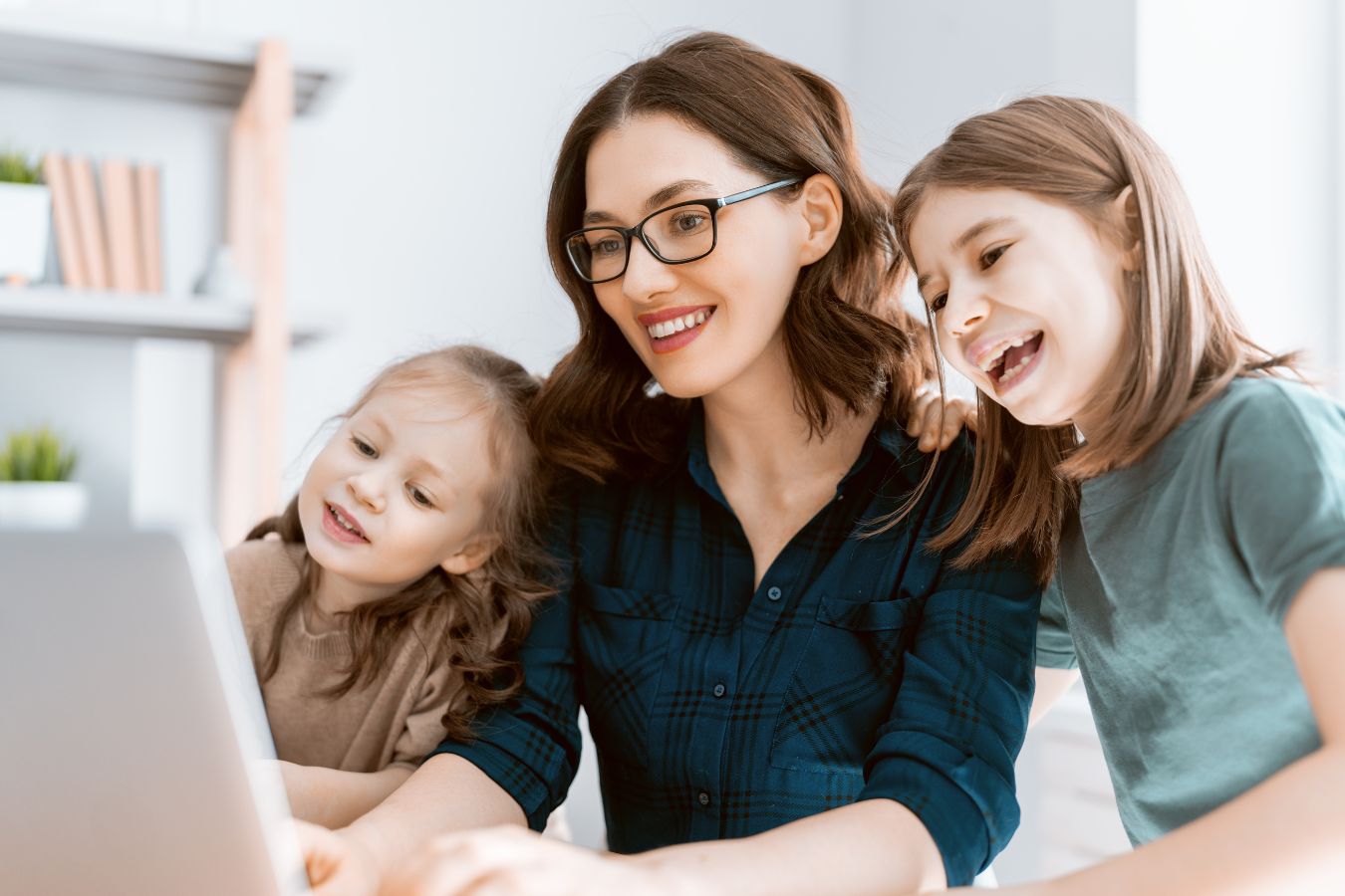 Picture of a woman using a laptop with her kids.