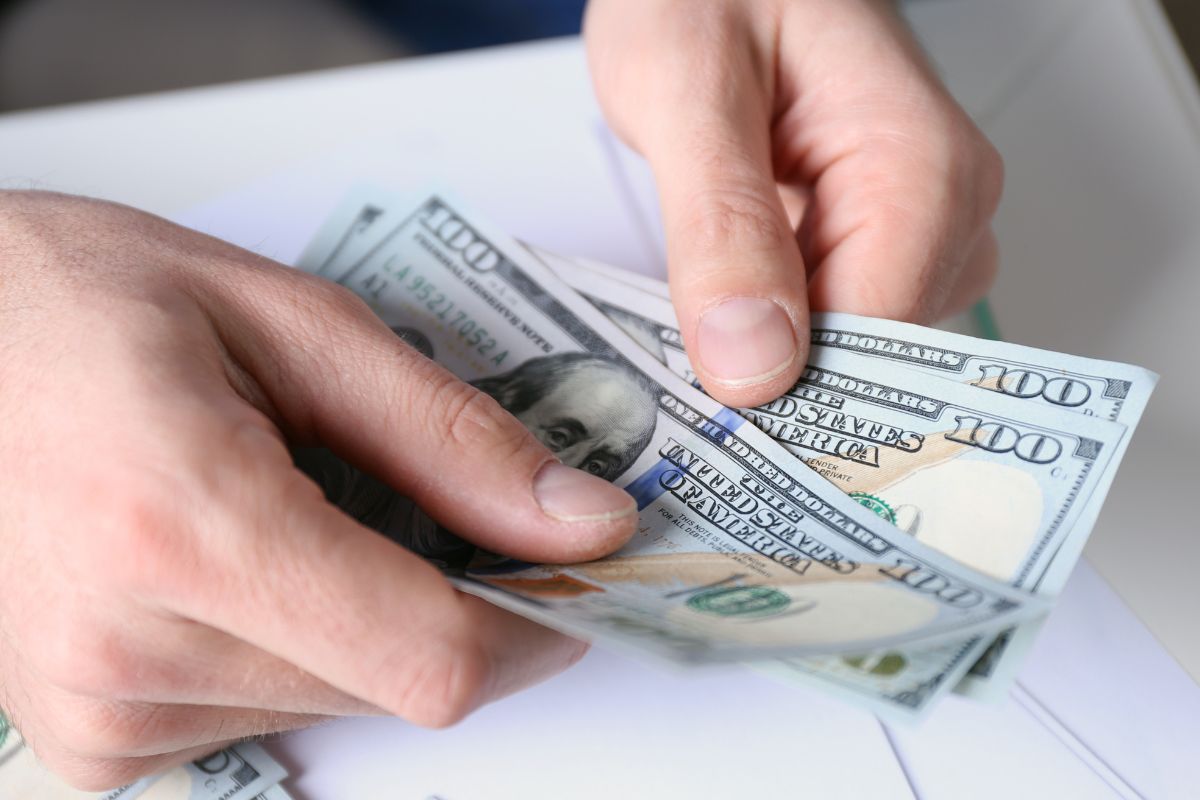A foto mostra a mão de um homem segurando dinheiro.