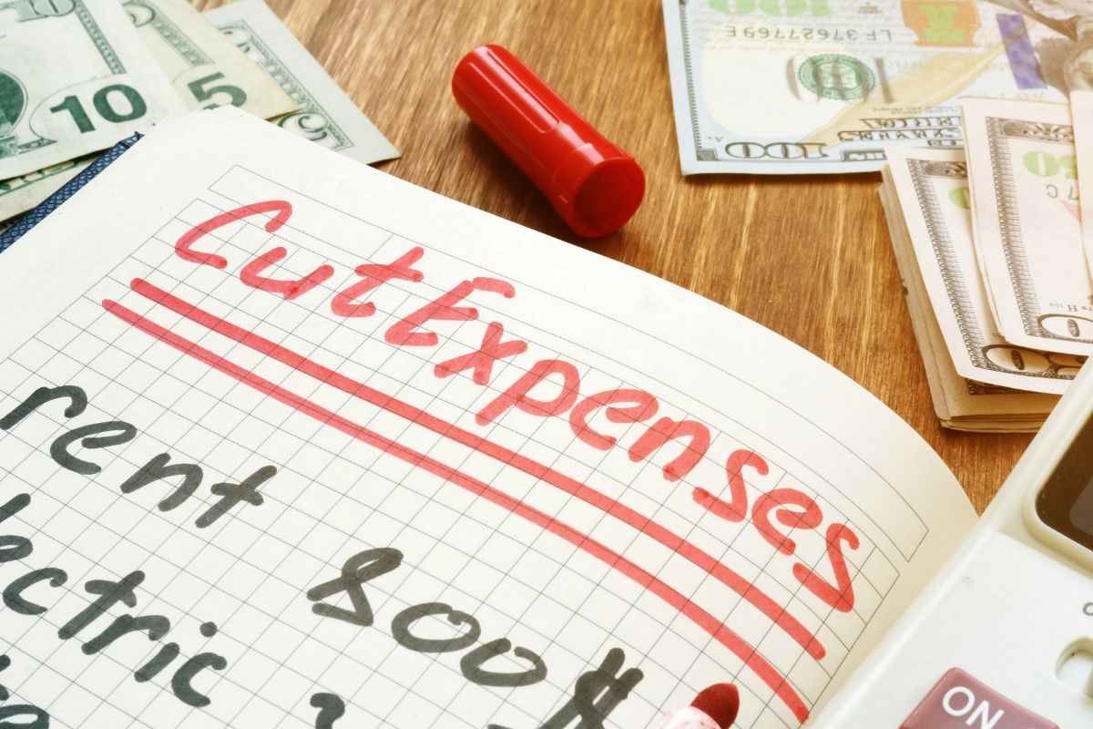 Picture of a notebook with cut expenses wording.