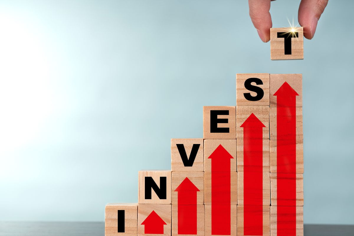 Photo de la main d'un homme construisant le mot investir.