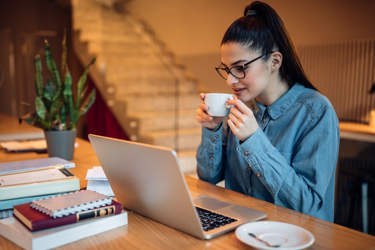 Picture of a woman using a laptop while having a coffee.
