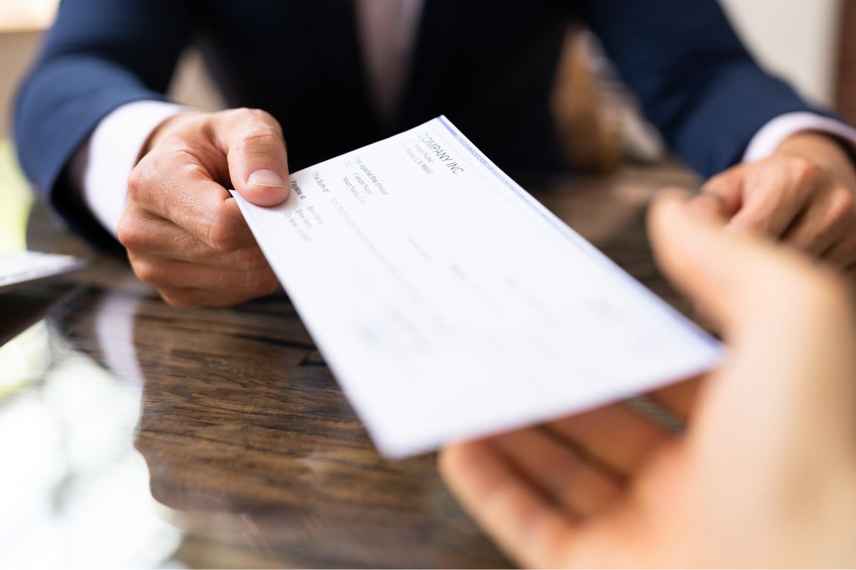 A woman's hand receiving a paycheck.