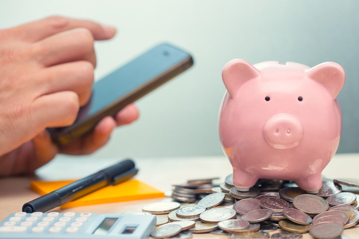 Photo of savings and a man's hand using a phone.