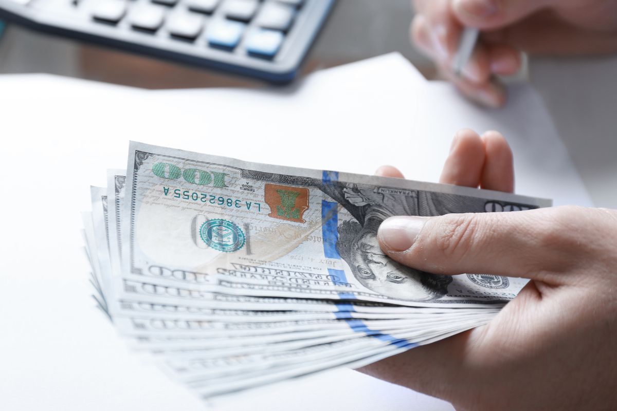 The photo shows a man's hand budgeting money.