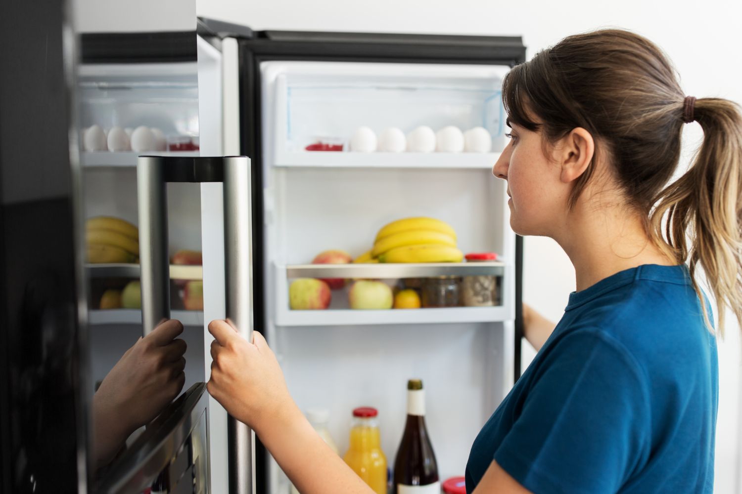 Imagem de uma mulher verificando a geladeira.