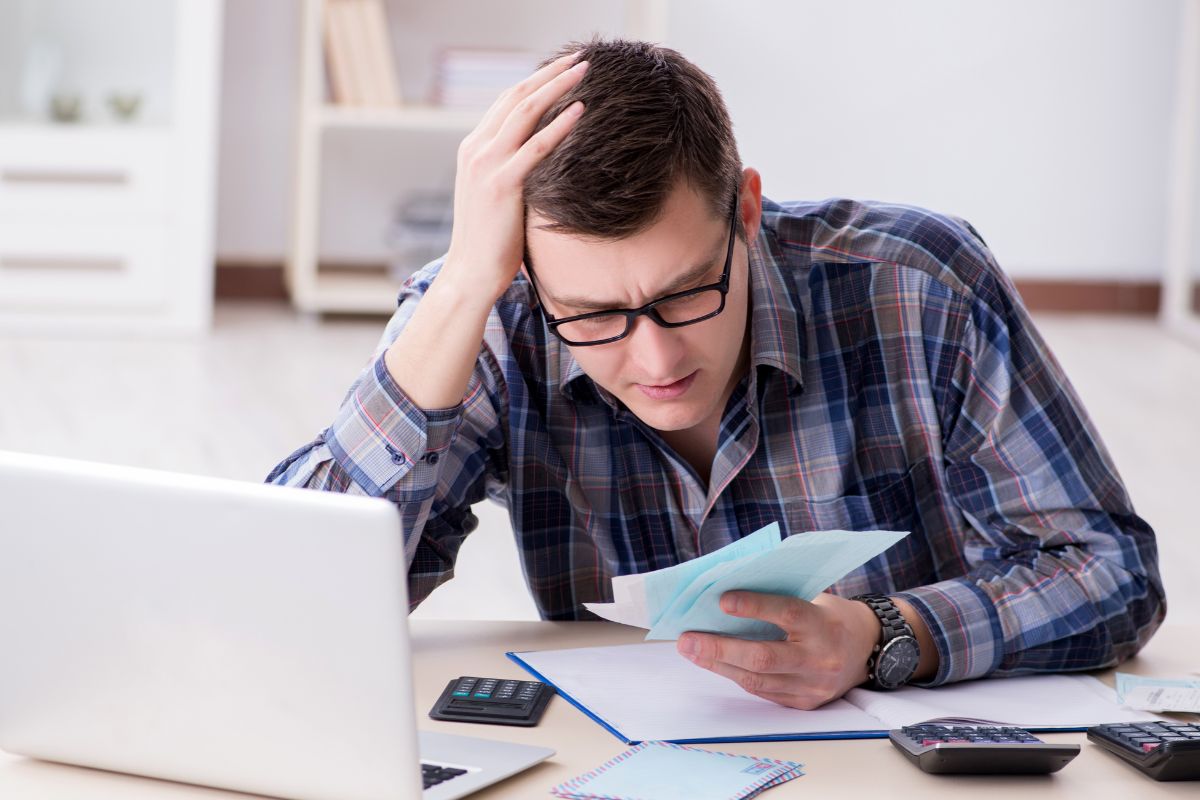 The image shows a frustrated man about his finances.