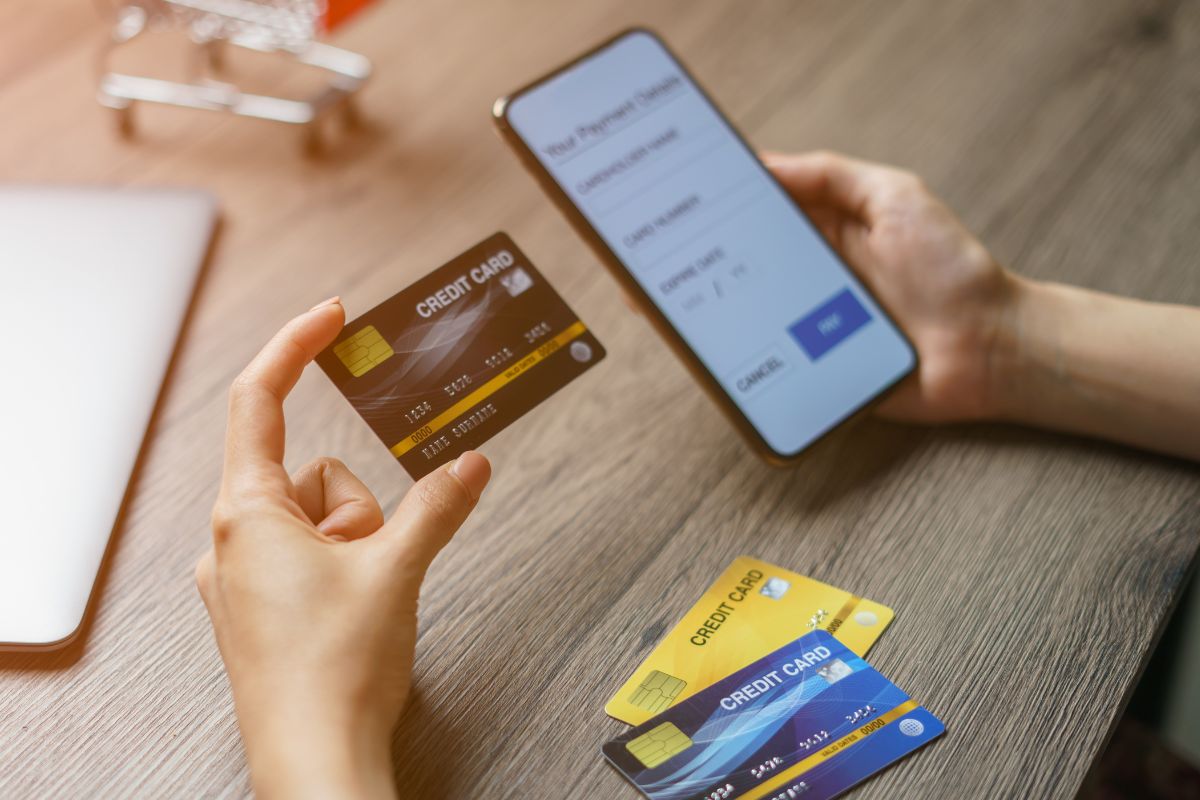 Photo of a woman's hand using a phone and credit card.