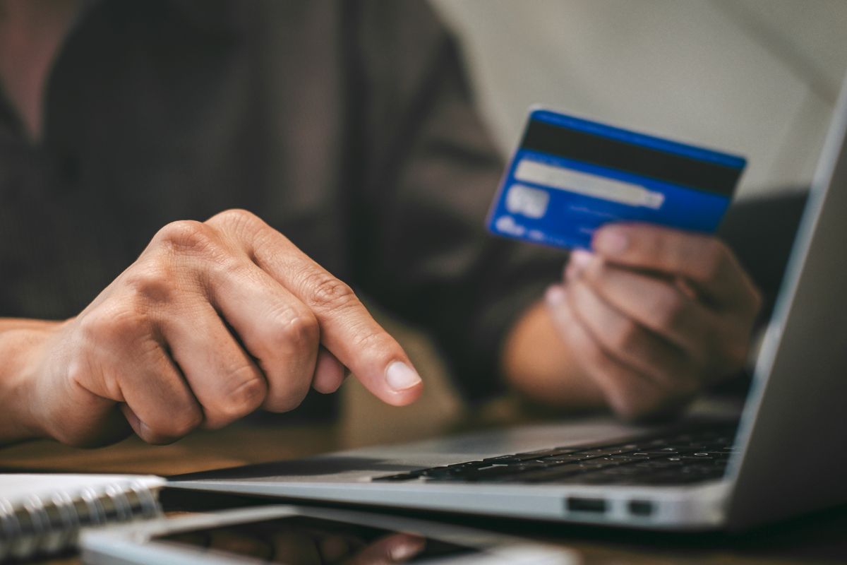 Image of a man's hand paying with a credit card.
