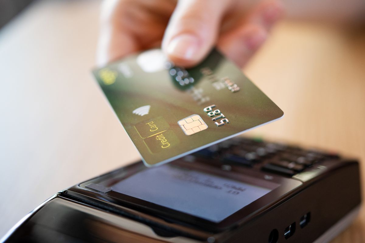 The photo shows a woman's hand paying with a credit card.