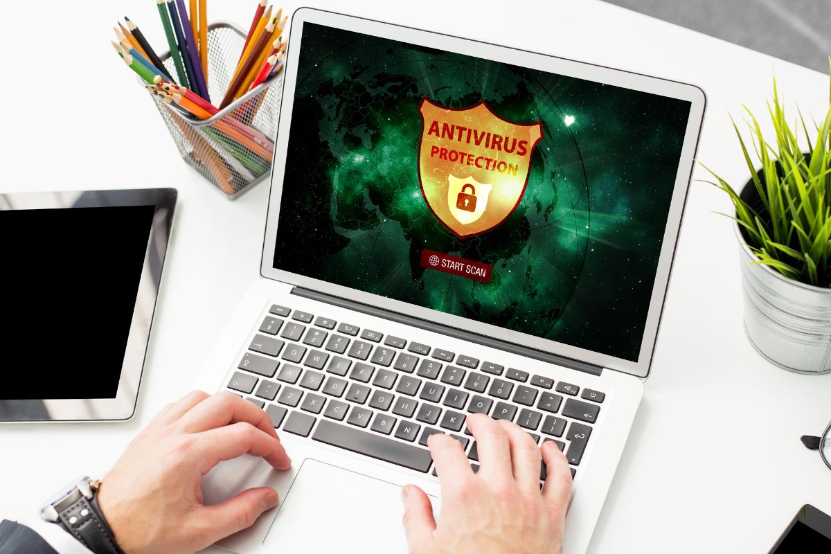 A man's hand using an anti-virus on a laptop.