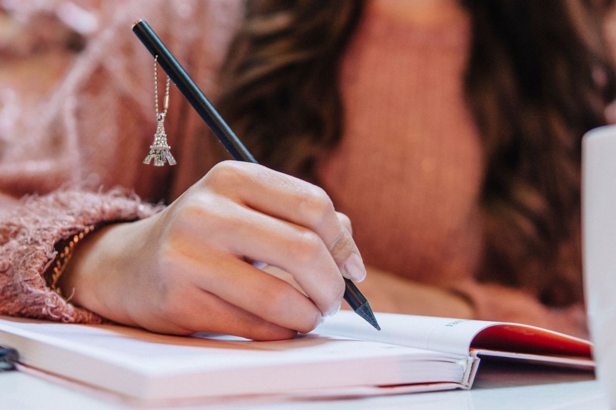 Photo of a young lady's hand making a list.