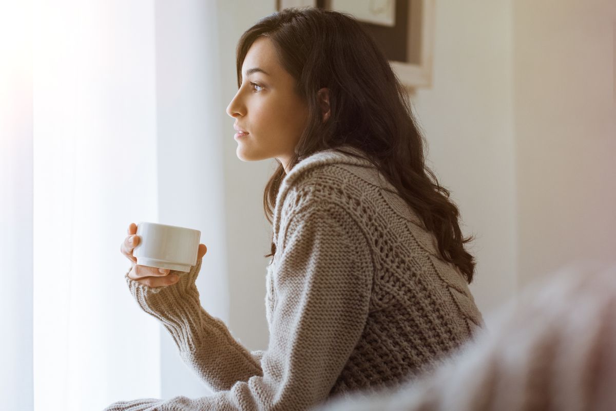 Une femme réfléchissant devant un café.