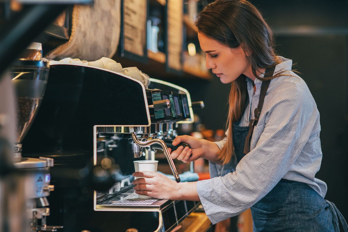 The image shows a woman making a coffee.