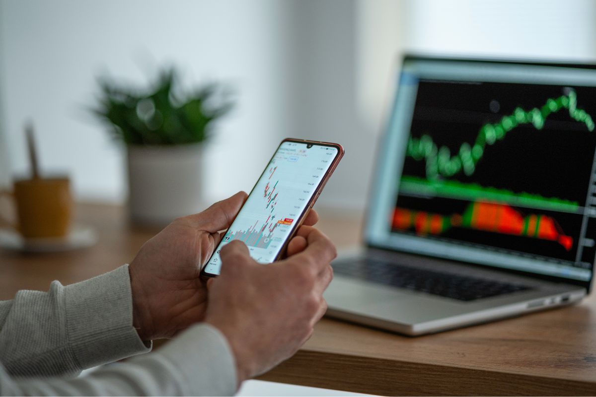 A man's hand investing in the stock market.