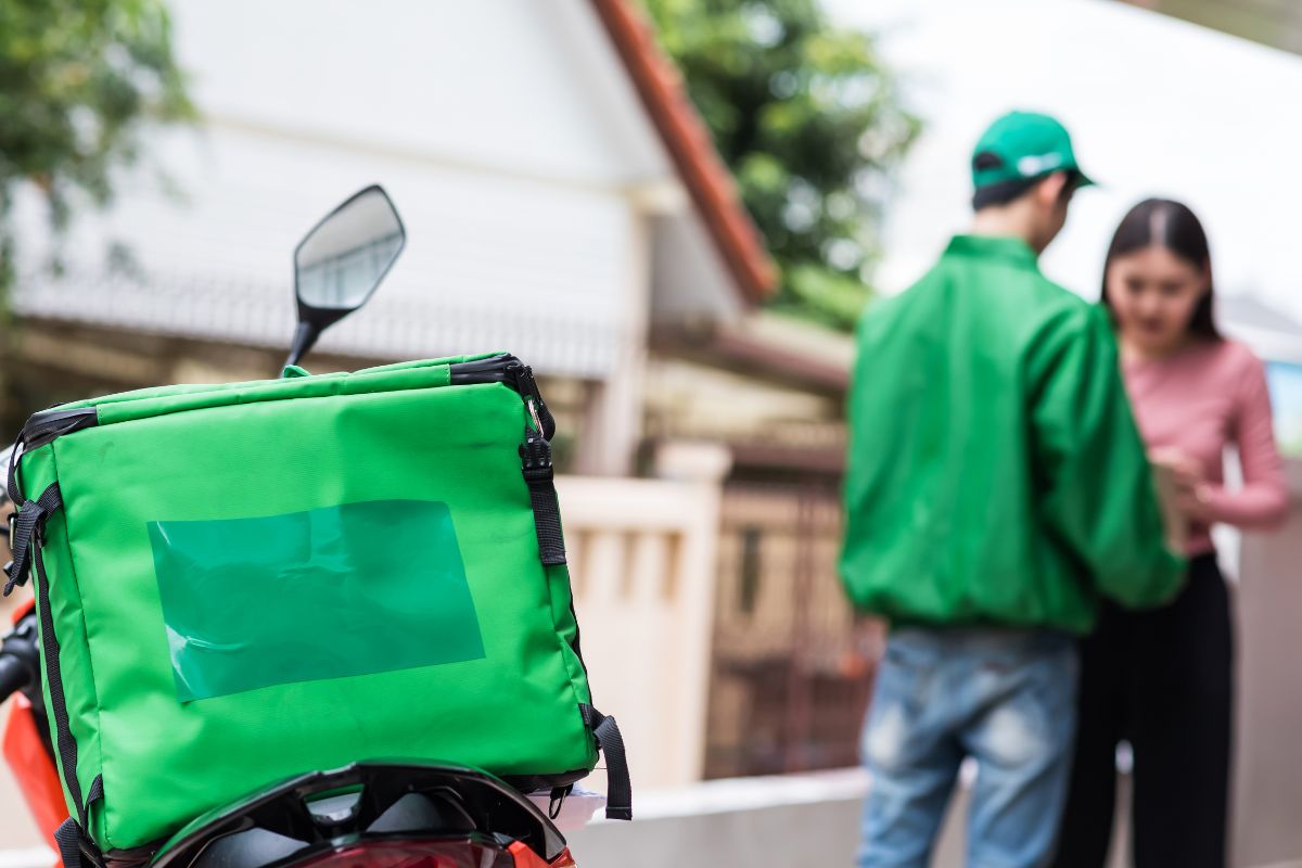 Picture of a deliveryman handing the orders to a customer.
