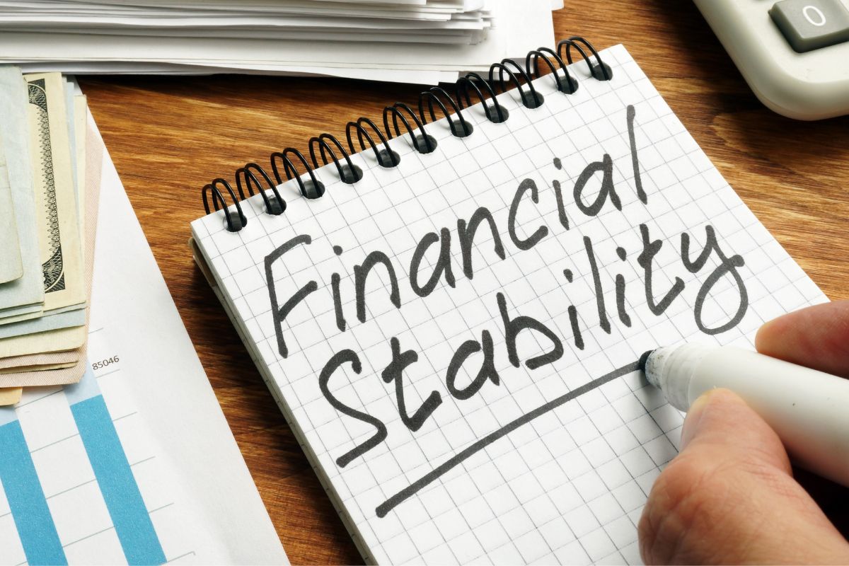 The picture shows a man's hand and writing financial stability.