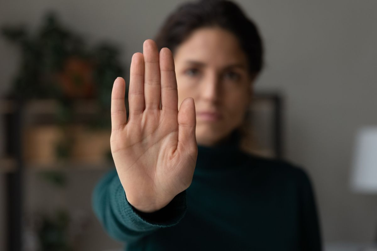 The picture shows a woman doing a stop sign.