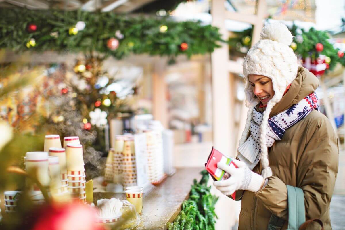 The picture shows a girl grabbing money from her wallet to buy in the coffee shop indicating to support local businesses and experiences that can boost the economy and build a sense of community.