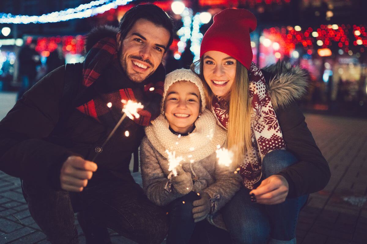 The picture of a family playing a burning sparkle together on Christmas Eve means that giving an experience over a gift can offer personalized and unique experiences.