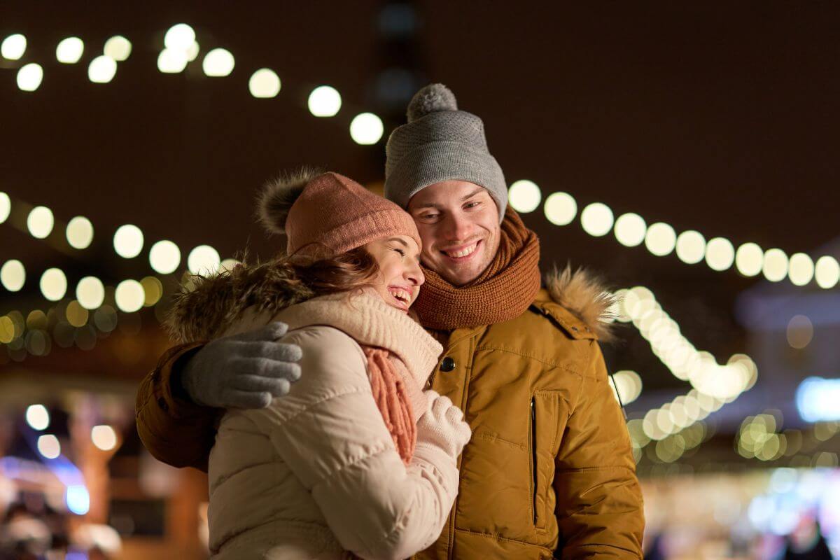 The photo shows a couple hugging each other indicating giving experiences on Christmas over gifts can be more meaningful and thoughtful and making them more personal.
