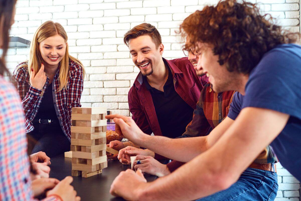 The photo shows a group of people playing wooden board games and enjoying which means that giving experience over gifts can encourage trying new things or unique adventures they haven't tried.