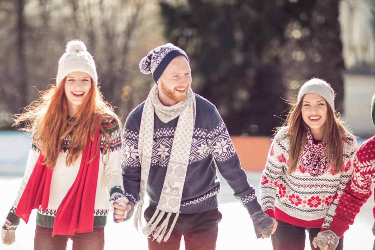 The picture tells about a group of people holding their hands together and enjoying the snow which means that giving experience over gifts helps less focus on materialism and helps appreciate life more than material possessions.