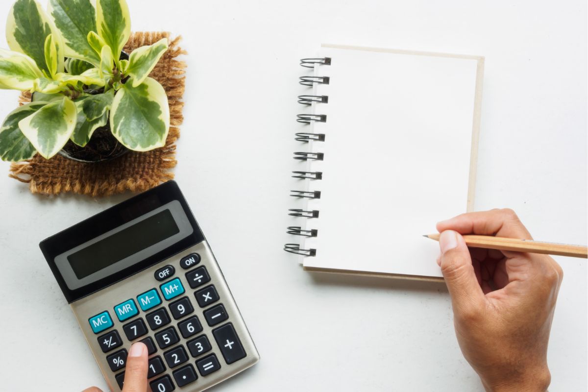 A man's hand calculating his monthly net pay.