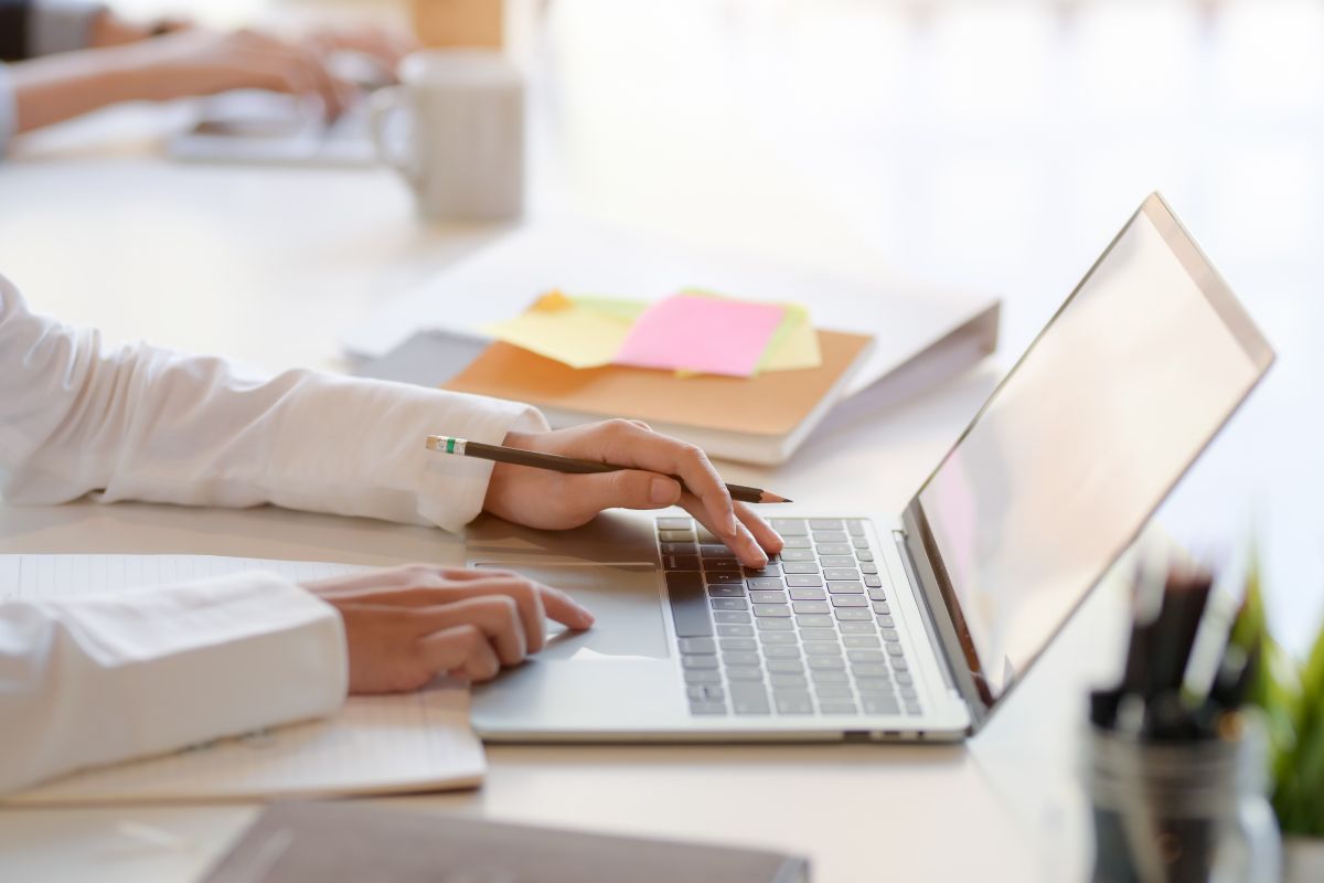 The photo shows a woman using a laptop.