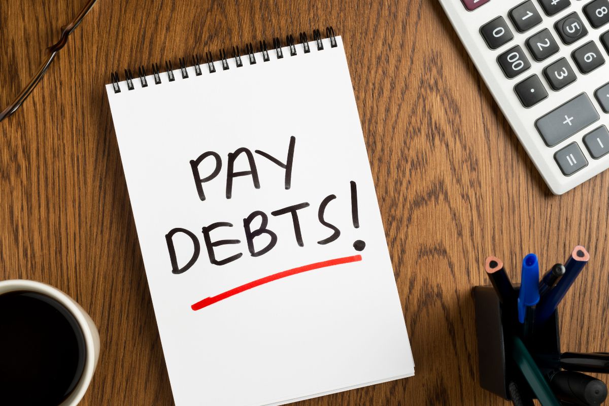 Un carnet avec l'inscription payer les dettes.
