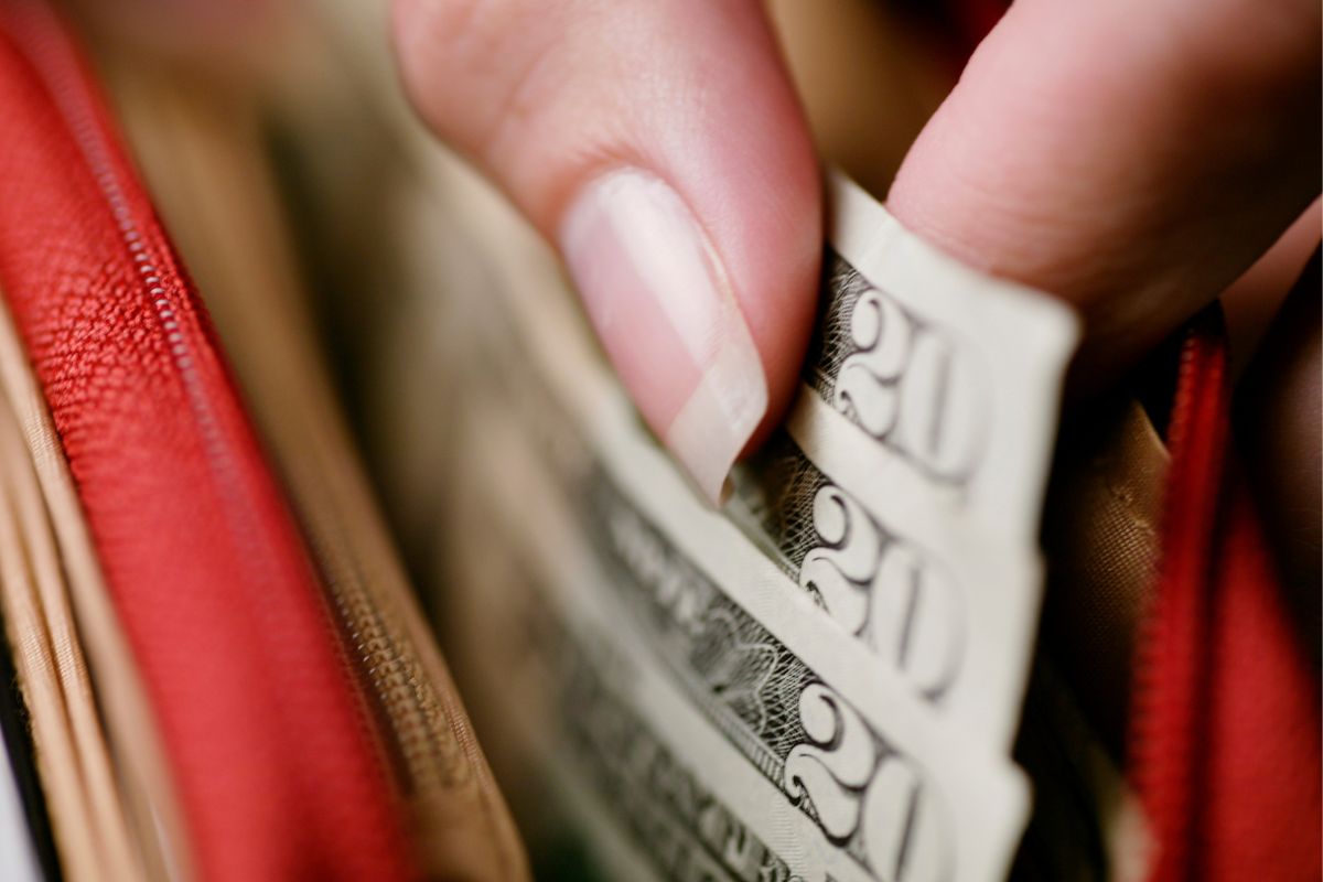 Une femme sortant de l'argent de son portefeuille.