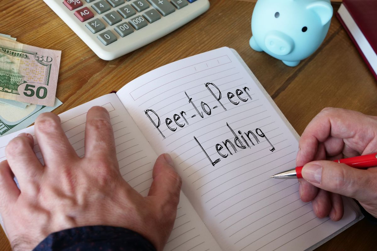 A man's hand is writing peer-to-peer lending on a notebook.