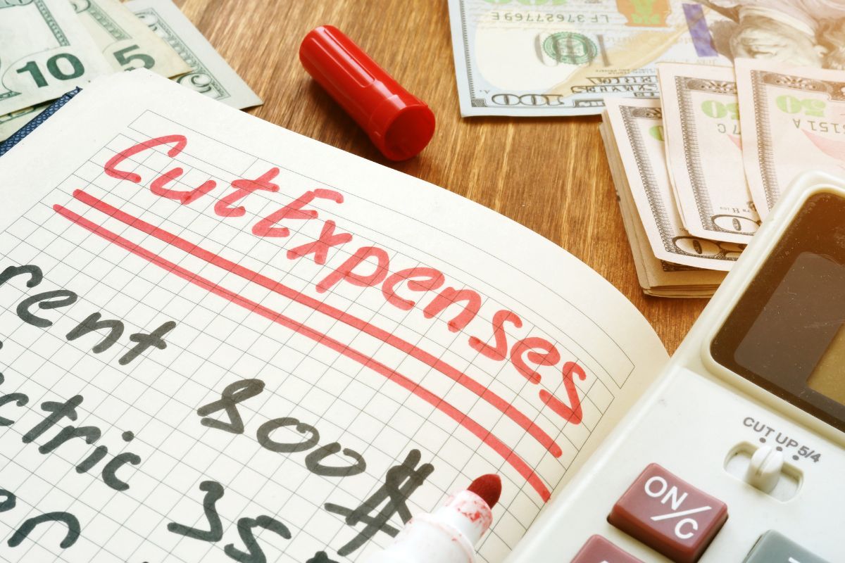 The photo shows a notebook with cut expenses wording.