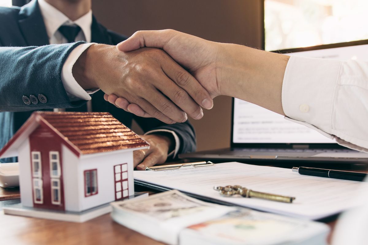Photo shows two hands shaking and dealing with real estate.