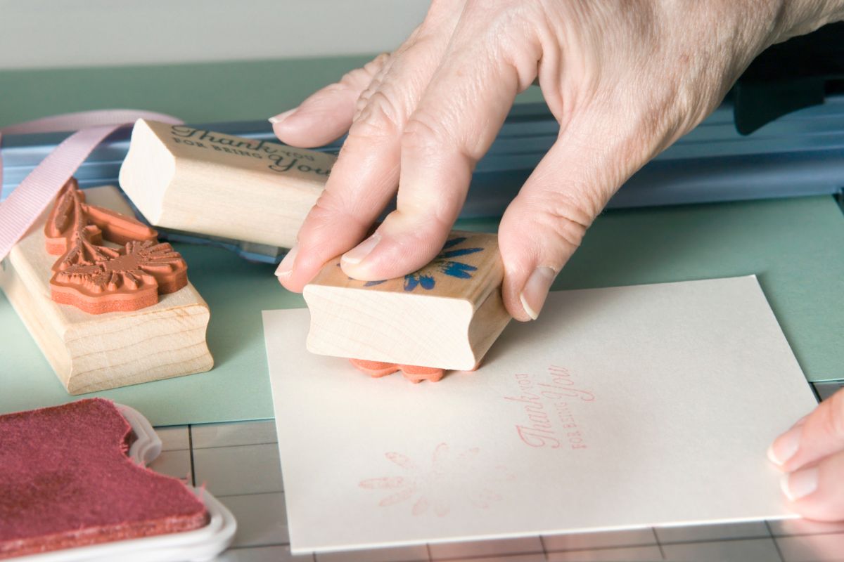 The photo shows a woman's hand stamping a paper.