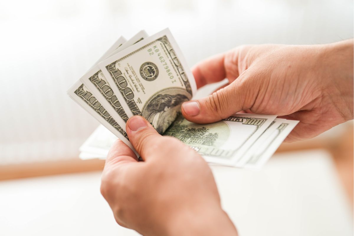 The photo shows a man's hand counting money.