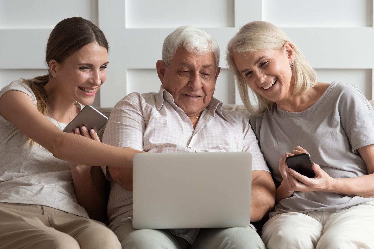 Image of a daughter teaching her aging parents using a laptop.