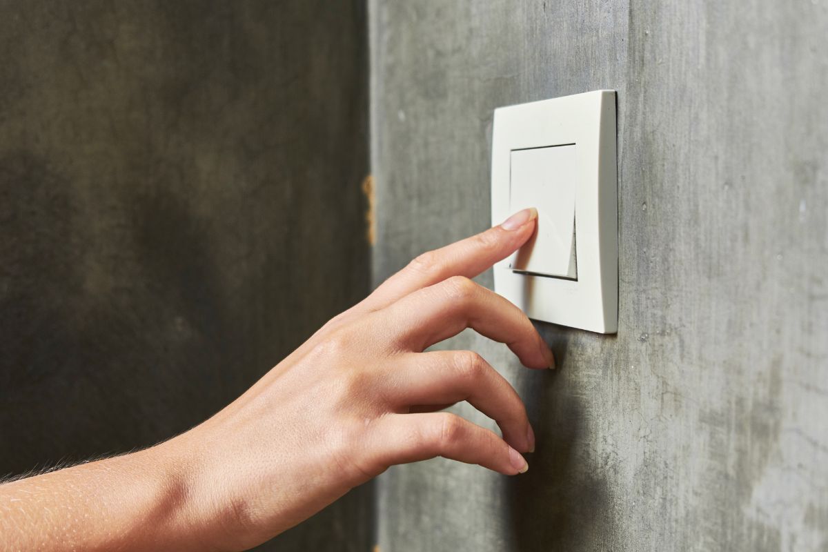 Photo of a woman's hand switching off the light.