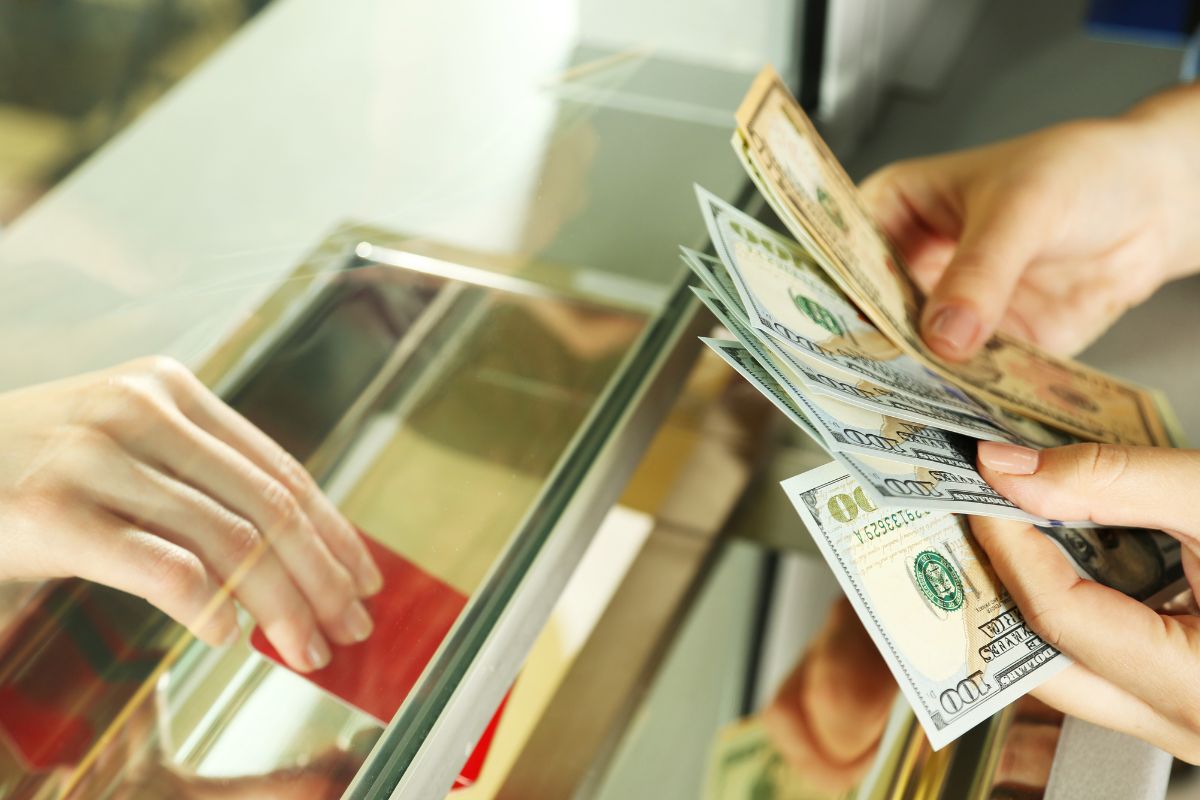 The photo shows a woman paying with cash.