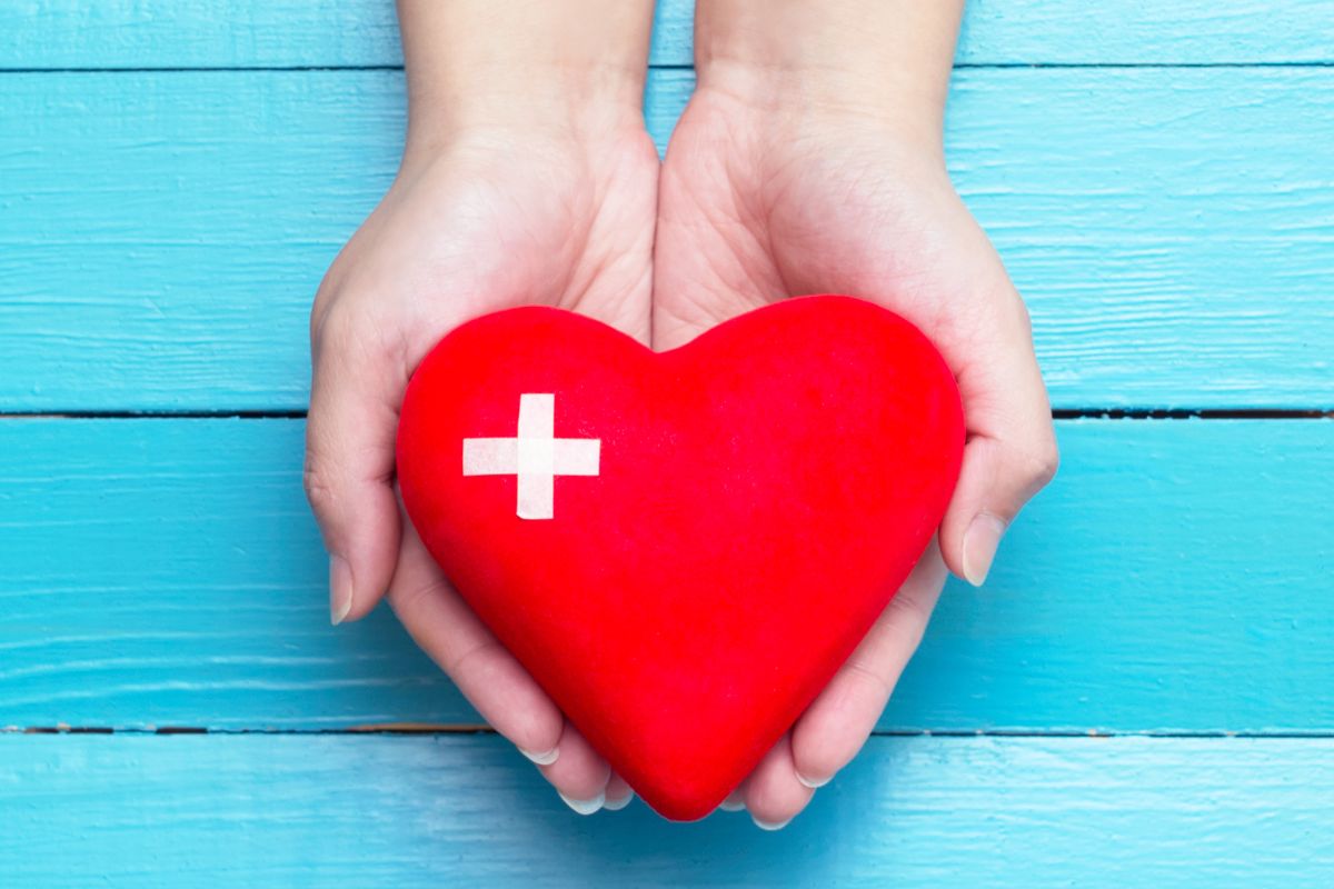 A woman's hand holding a heart with ex sign.
