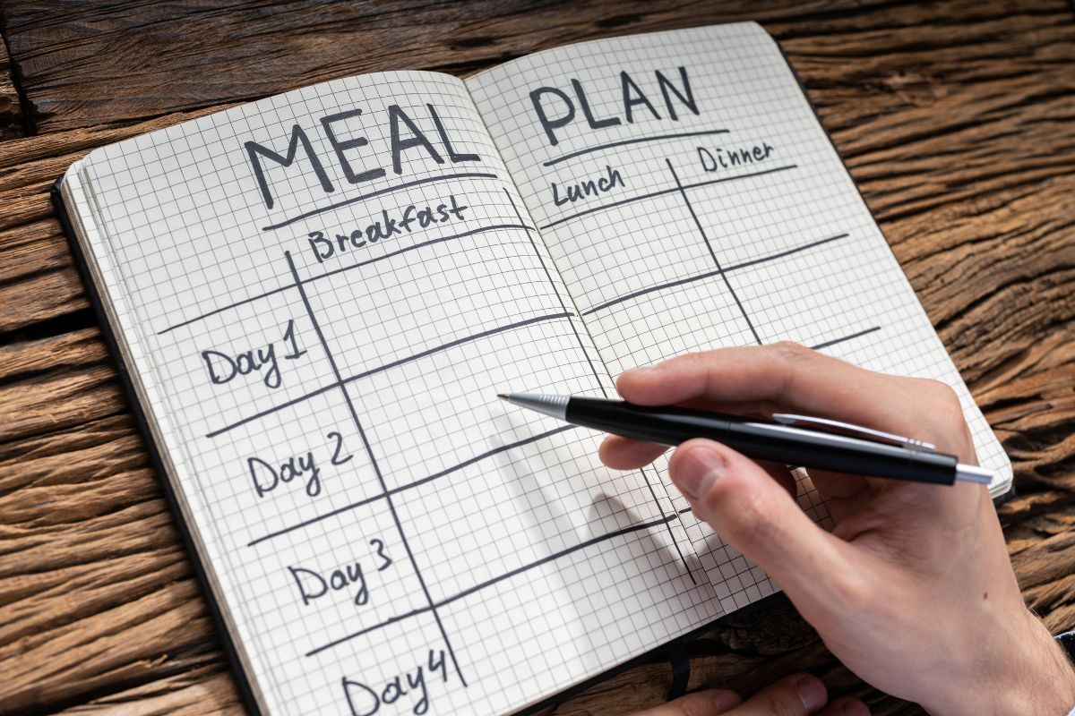 A man's hand creating a meal plan.