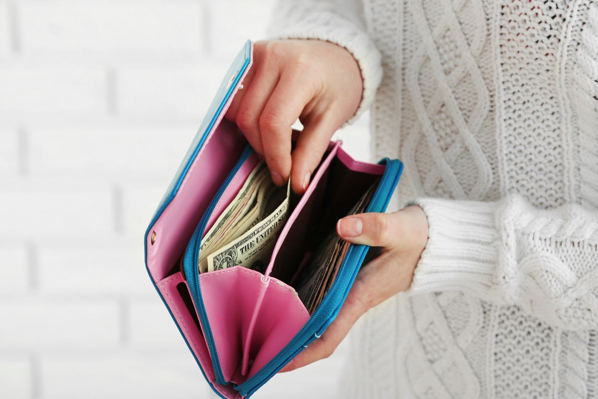 A woman's hand putting her money in her wallet.
