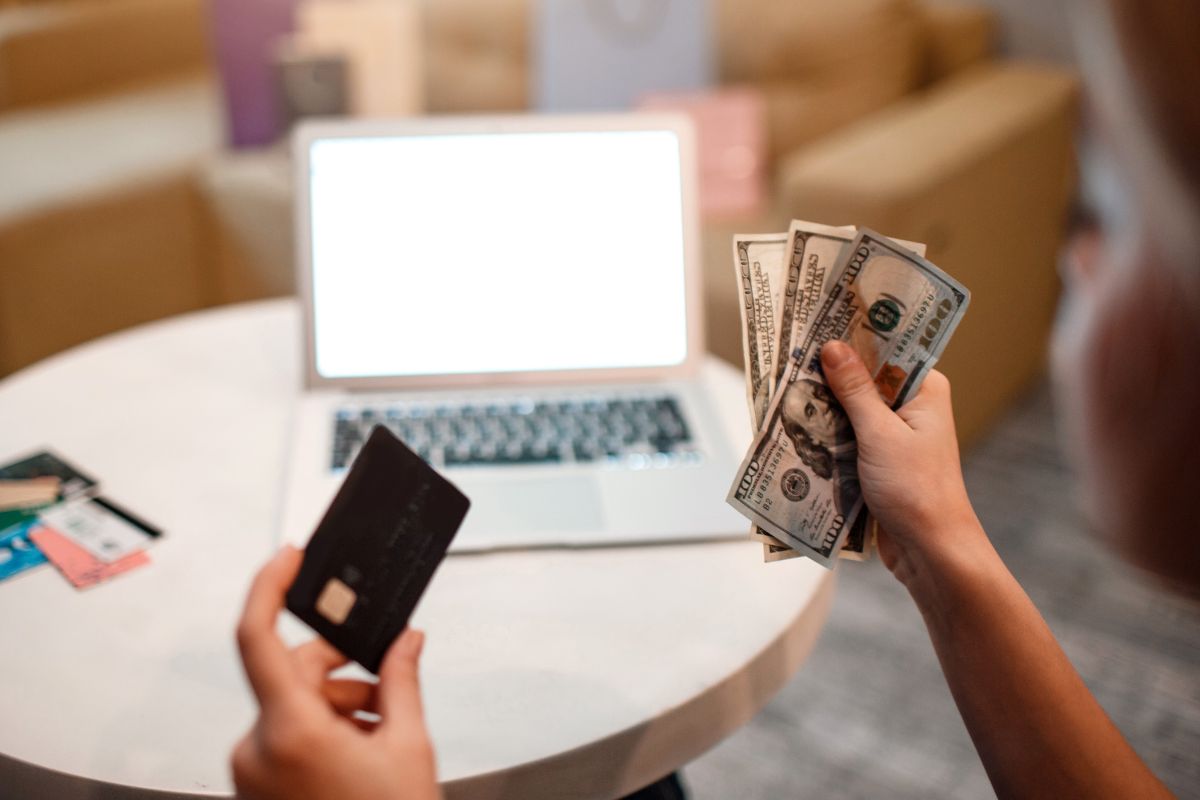 A woman's hand holding a credit card and money.