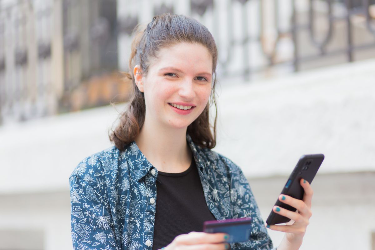 Image of a young lady using a phone and credit card.