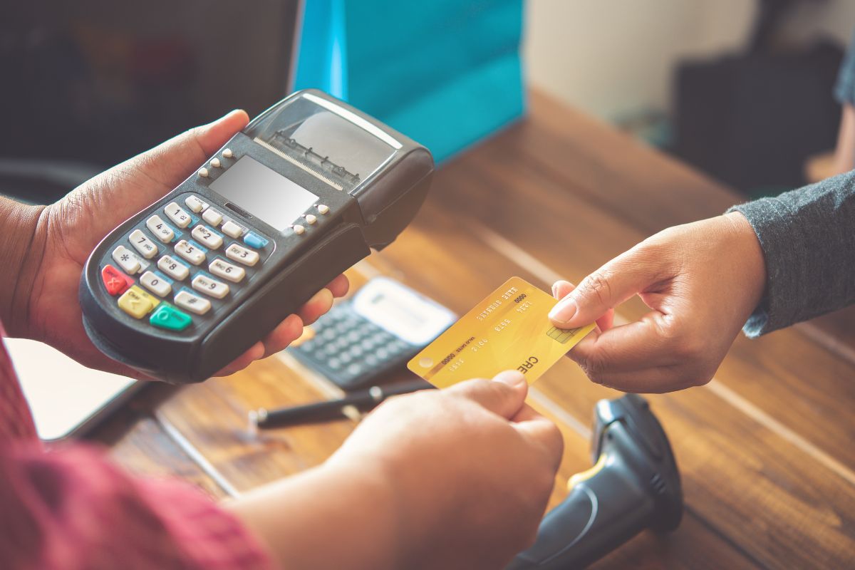 Photo of a man's hand paying with a credit card.