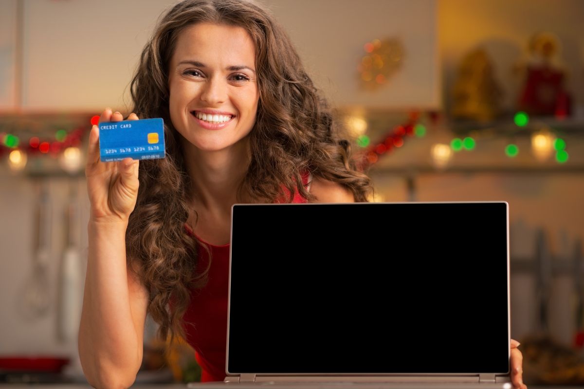 A woman holding a laptop and a credit card.