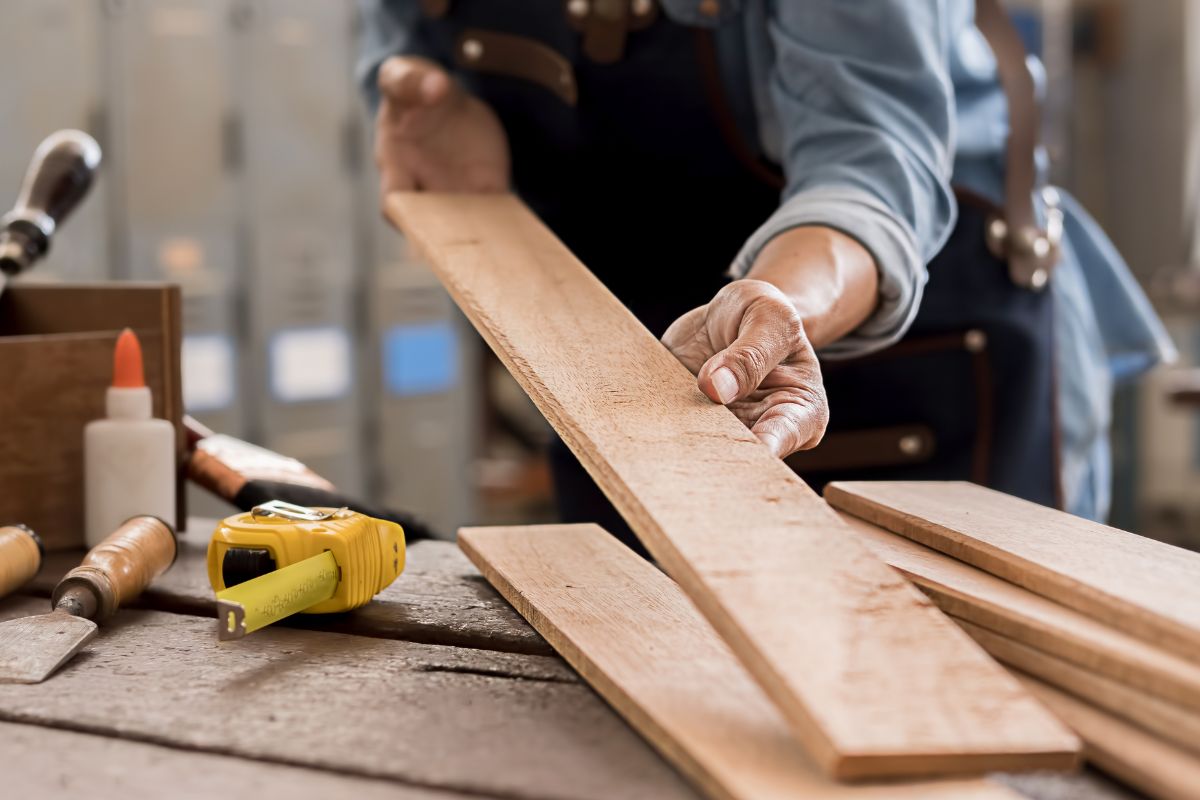 The photo shows a carpenter holding a wood.