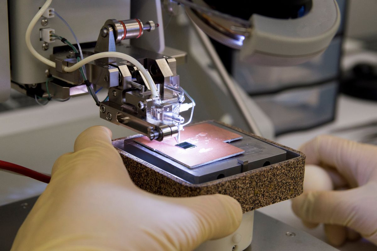 Picture of a man's hand working on a wire bonder.