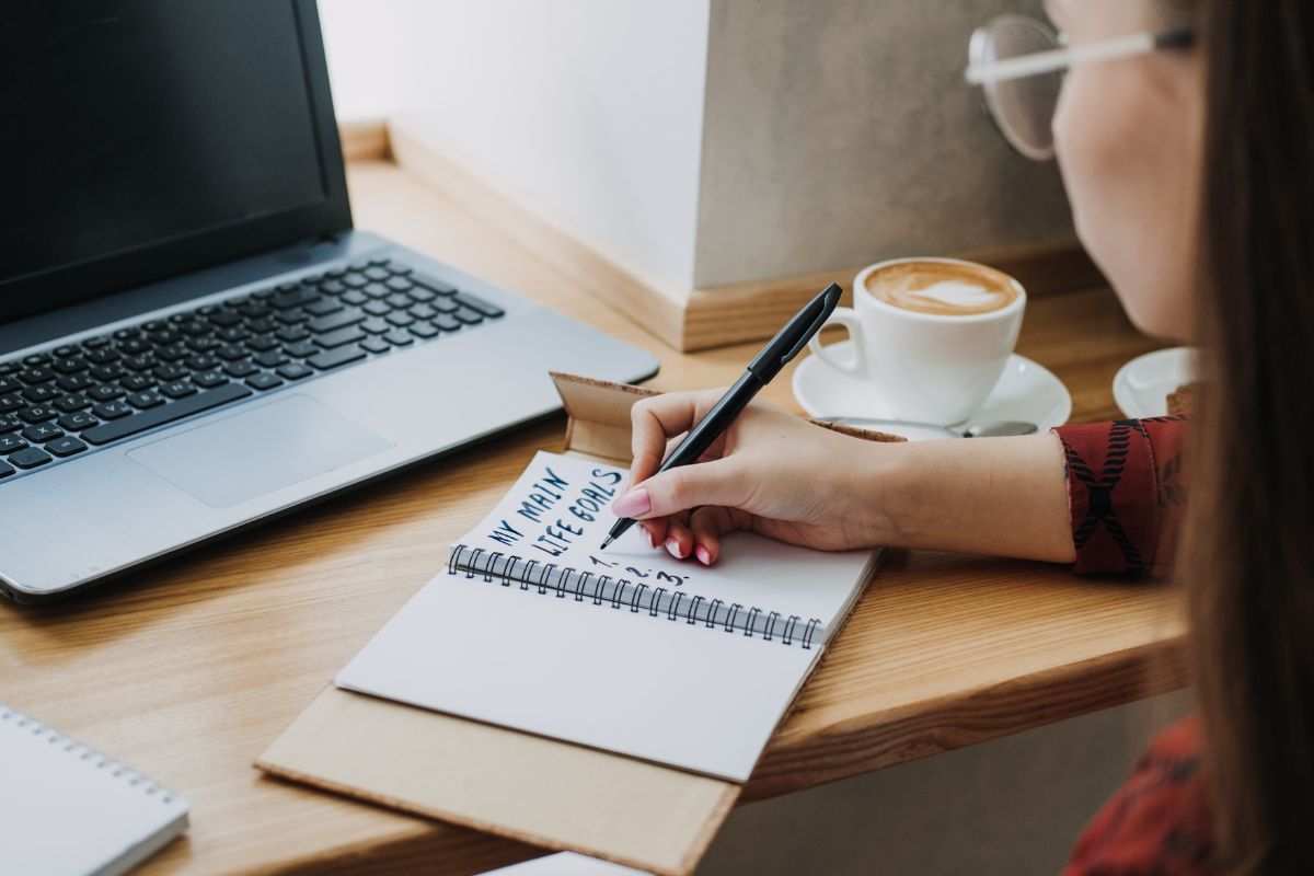 La photo montre une femme écrivant ses objectifs.