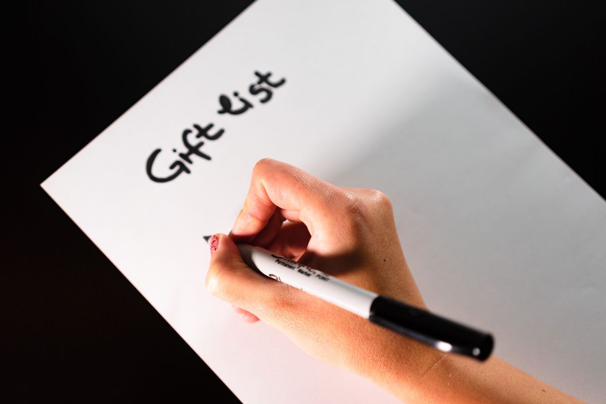 A woman's hand is making a gift list.