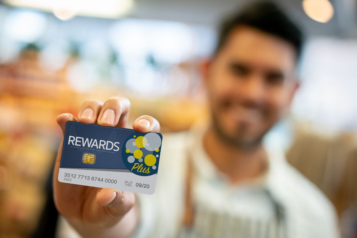 A man's hand holding a reward card.